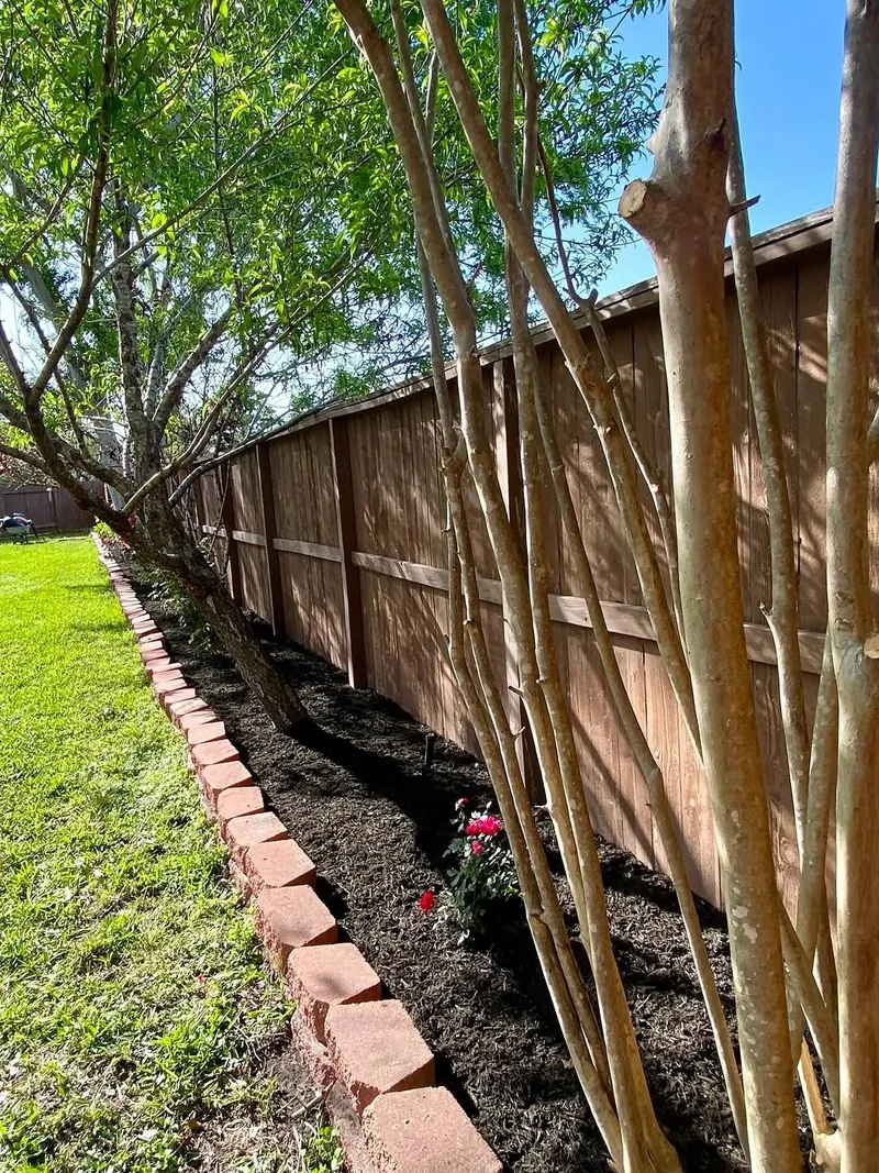 Brick-edged flower bed along a fence line