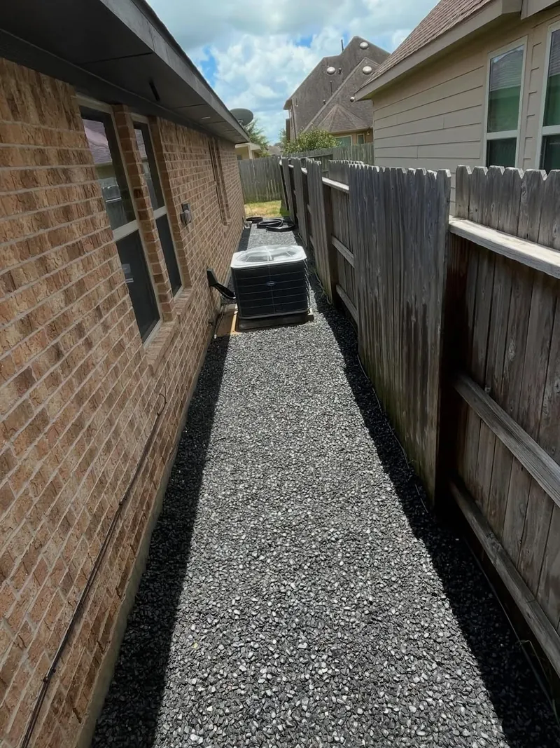 Side yard finished with gravel along a wood fence